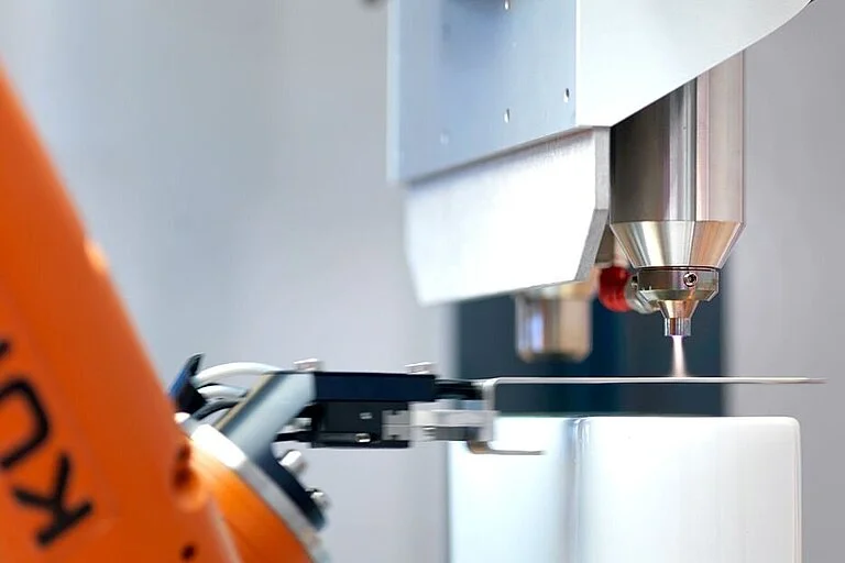 Braço robótico industrial realizando um tratamento de superfície com plasma atmosférico.